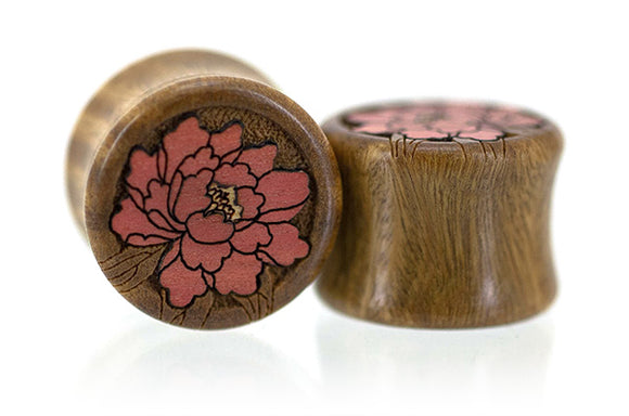 A pair of wooden ear plugs with a floral inlay design, crafted from Verawood with Pink Ivory and Osage Orange Inlay details.