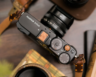 Custom made wood camera button and hot shoe cover displayed on a Fuji camera. 
