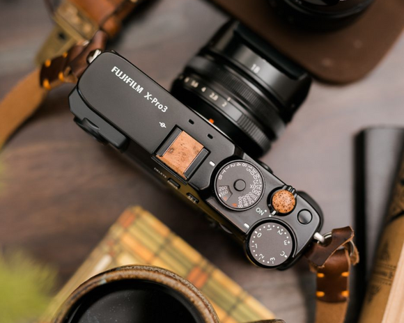 Custom made wood camera button and hot shoe cover displayed on a Fuji camera. 