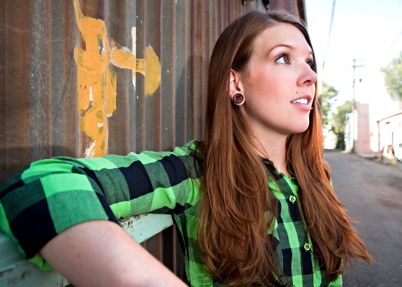 Women posing against metal wall modeling Button Plugs.