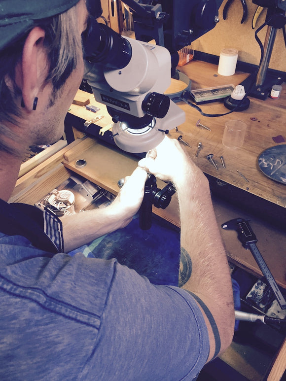 Working on a jewelers bench setting the stone in a custom made ring. 