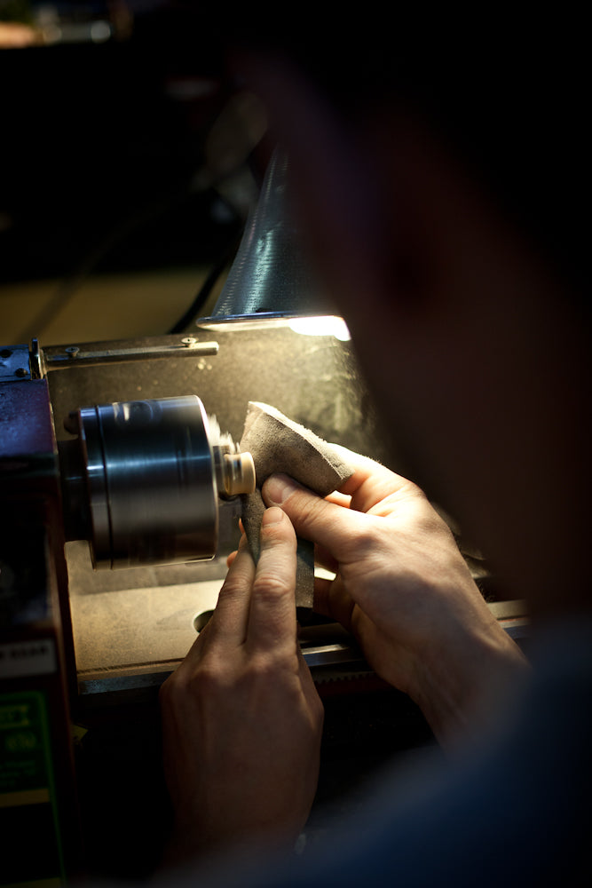 Hand sanding a wood ear gauge plug on a lathe. 