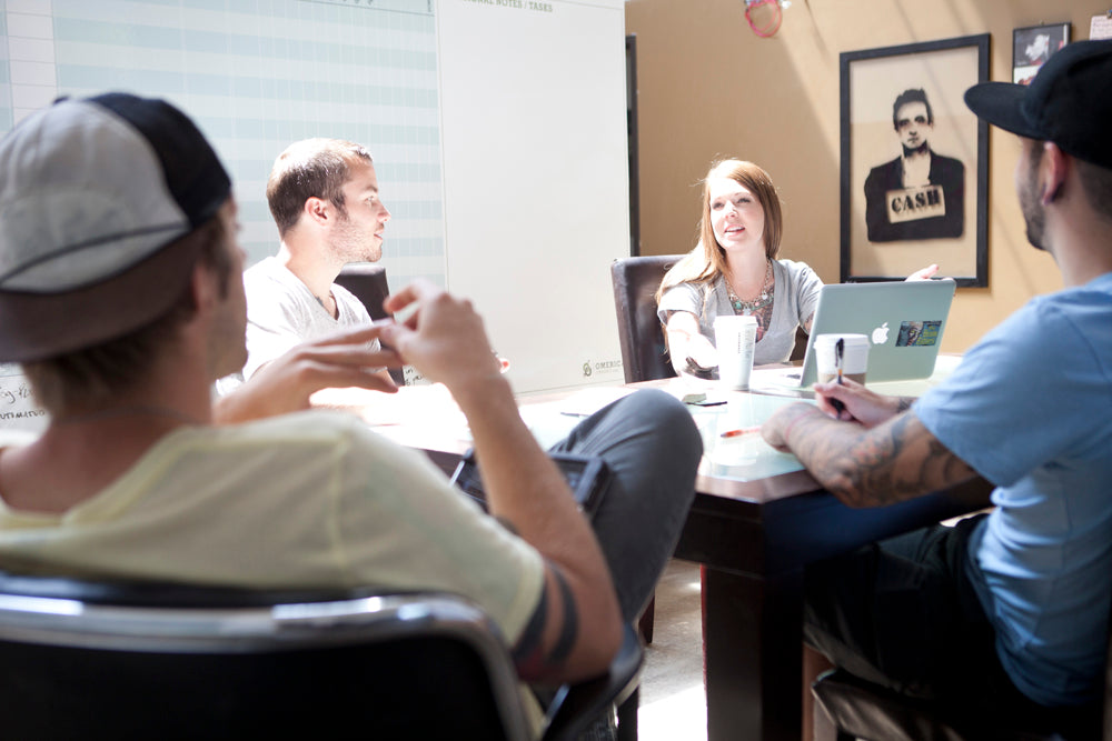 Four people sitting around table for a meeting. 