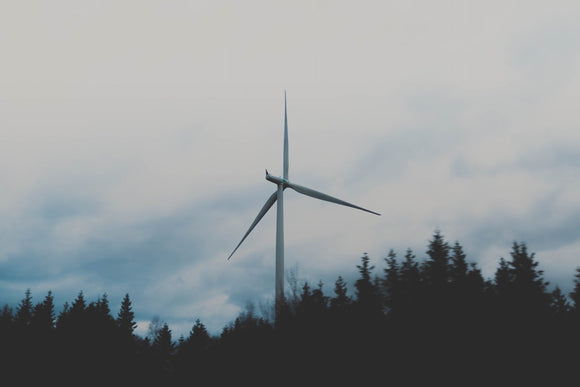 Wind turbine with clouds and trees in background.   