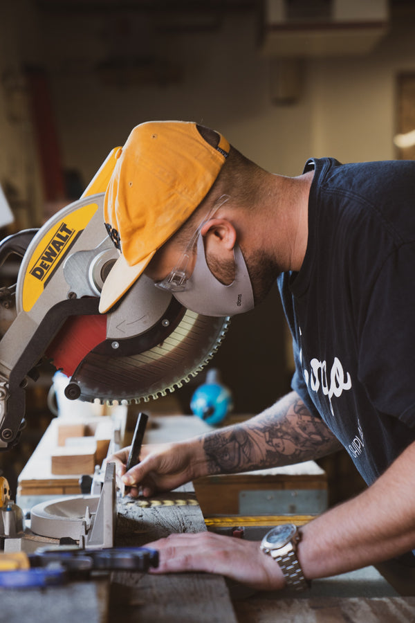 Craftsman measuring wood to cut on chop saw. 