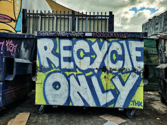 Recycle dumpster covered in graffiti. 