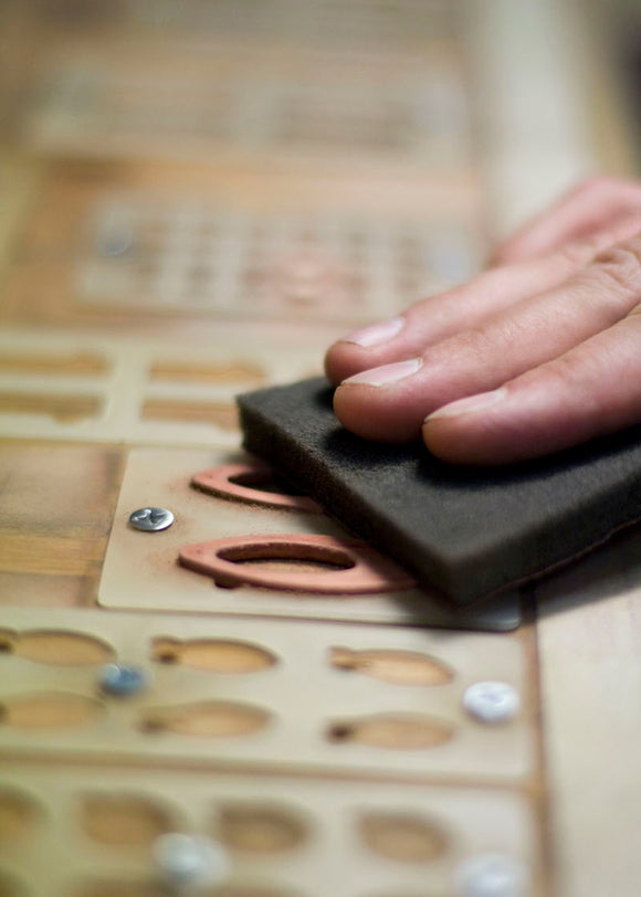 Hand sanding a pair of wood earrings. 