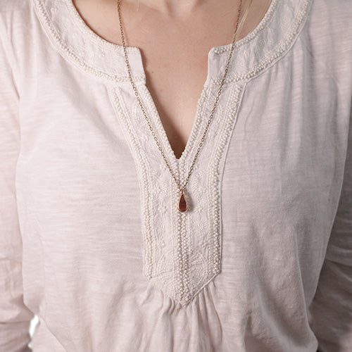 Rain drop pendant worn by customer. Bronze metal with Bloodwood inlay. 